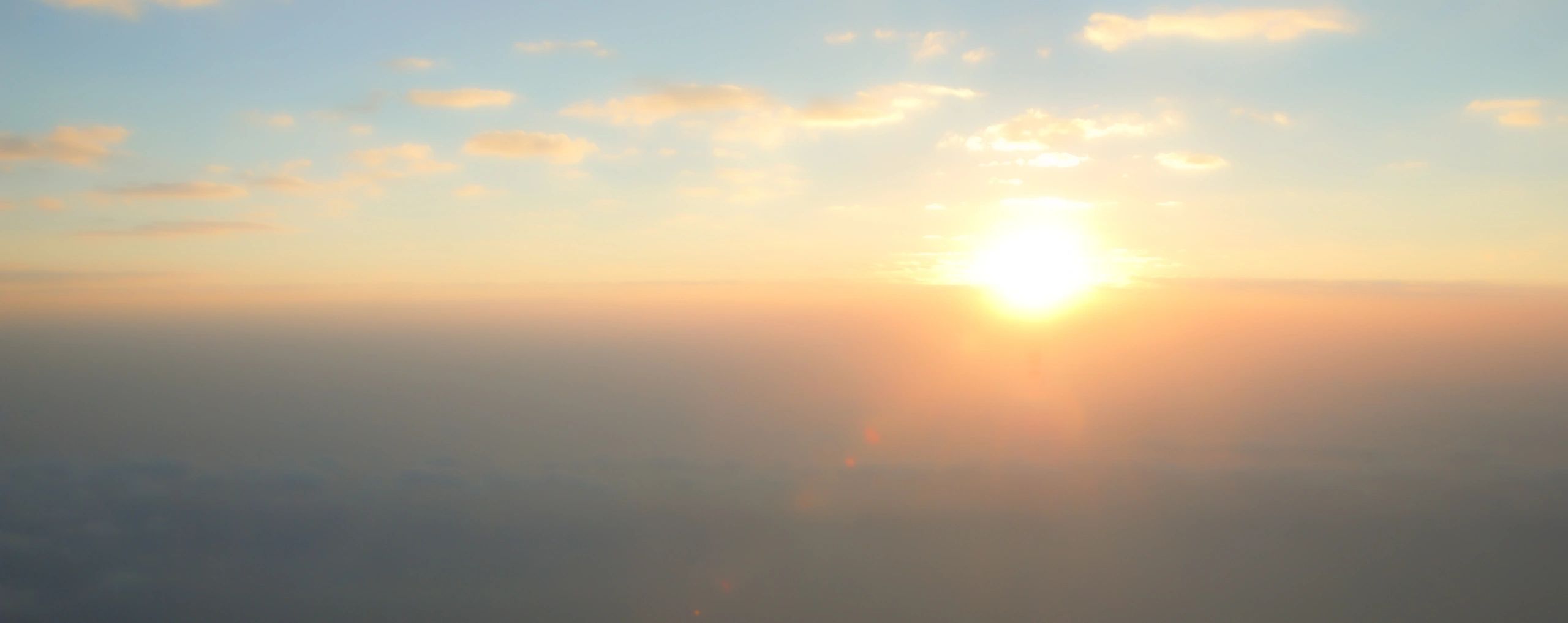 Airplane wing above clouds at sunrise